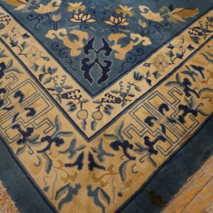 Ornate blue rug with gold and cream floral motifs lies on distressed wooden floorboards.