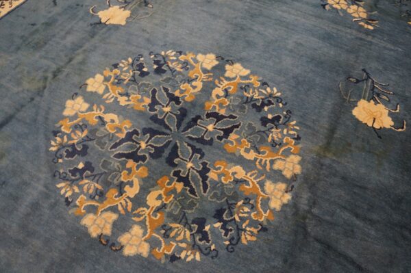 Blue rug with a detailed circular floral pattern in cream, gold, and dark blue.