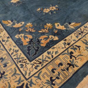 Teal rug with thick floral border featuring gold, tan, and dark blue patterns over wood flooring.