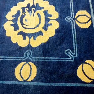Navy blue rug with a plush pile featuring large golden yellow floral patterns and light blue borders.