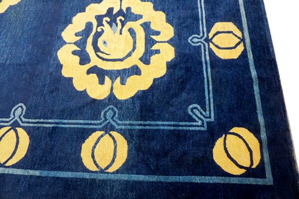 Navy blue rug with a plush pile featuring large golden yellow floral patterns and light blue borders.