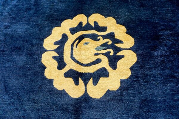 Plush dark blue rug with a centered gold dragon-like motif and subtle teal accents.