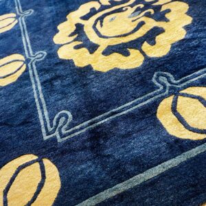 Plush, indigo rug displaying a bold yellow floral motif and light blue decorative bordering.
