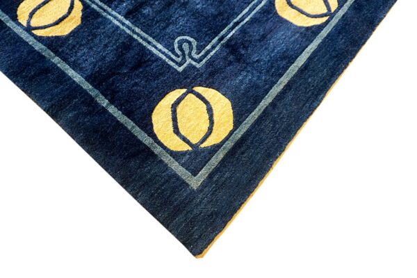 Detail of a navy blue rug corner featuring yellow circular patterns and light blue geometric borders.