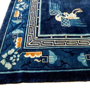 Plush navy blue rug with detailed light blue, cream, and tan oriental borders and central bird pattern.