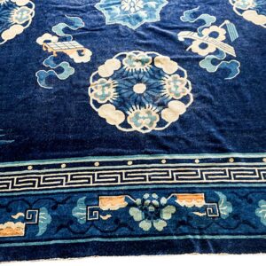 Dark blue velvety rug with pale blue and cream floral patterns, stylized birds, and a geometric border.