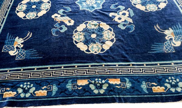 Dark blue velvety rug with pale blue and cream floral patterns, stylized birds, and a geometric border.