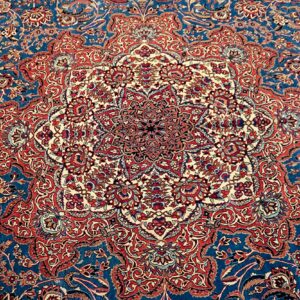 Detailed rug pattern with a large central medallion and dense red and cream florals on a deep blue field.