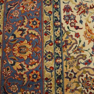 Close-up of an ornate rug featuring blue and cream fields, red borders, and detailed gold and red floral motifs.