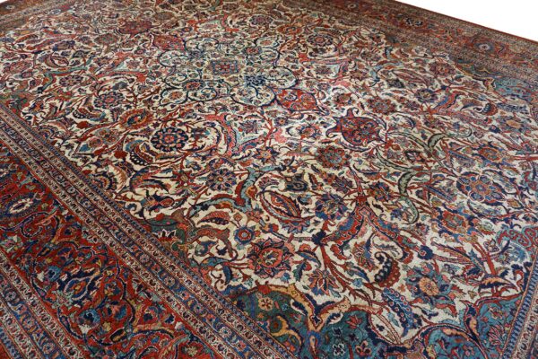 Cream rug with an all-over traditional design of scrolling vines, deep red, and blue motifs.