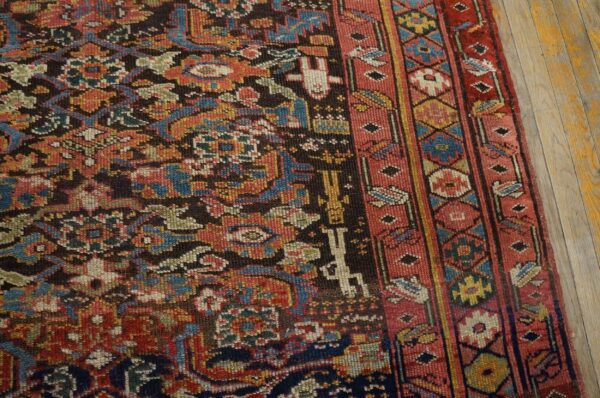 Detailed traditional rug in dark red, navy, and black with floral and geometric motifs on distressed wood floors.