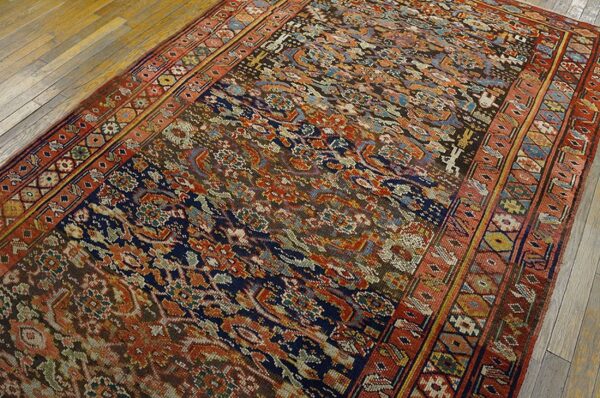 A complex patterned rug in rust, navy, brown, and light blue rests on light plank wood flooring.