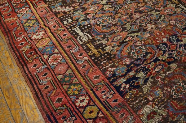 Low-pile rug detail featuring red, blue, and dark brown traditional patterns rests on light wood flooring.