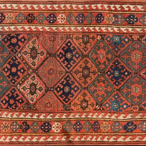 Low-pile geometric runner featuring interlocking red, navy, and teal diamond motifs and multi-layered borders.