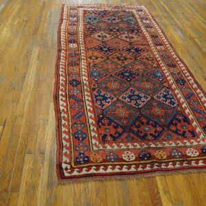 Geometric runner rug featuring rust, navy, and cream colors lies on wide plank hardwood floor.