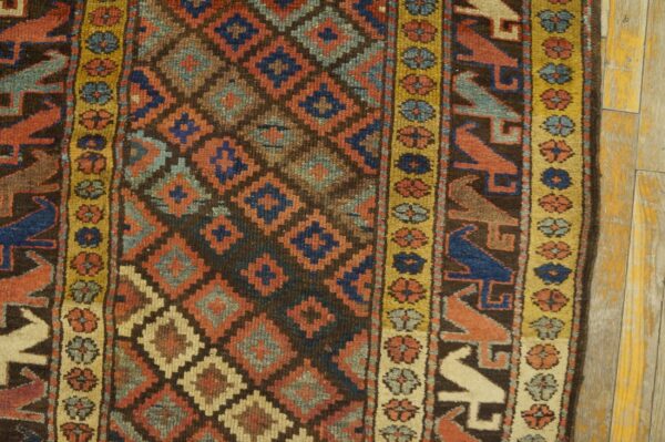 A tightly cropped rug features a diamond pattern and bird motifs in red, blue, and dark brown.