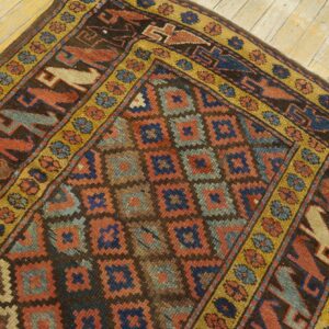 Brown, rust, and blue low-pile geometric rug featuring stylized animal borders on light wood floor.
