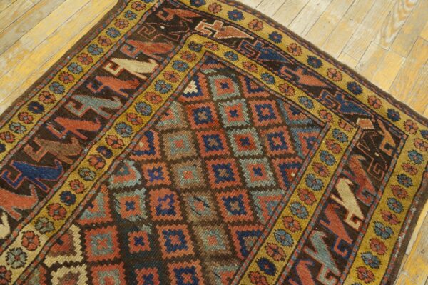 Brown, rust, and blue low-pile geometric rug featuring stylized animal borders on light wood floor.