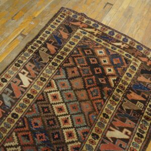 Geometric rug featuring dark brown, blue, and rust colors with stylized figures on distressed wood planks.