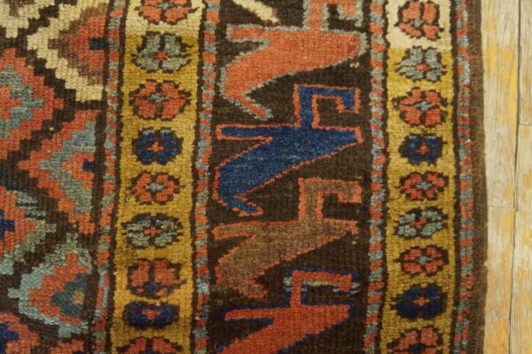 High-pile rug detail showing geometric patterns in rust, blue, and gold against light wood flooring.