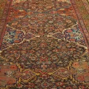 Muted red and blue traditional rug with complex pattern and central medallion on light wood flooring.