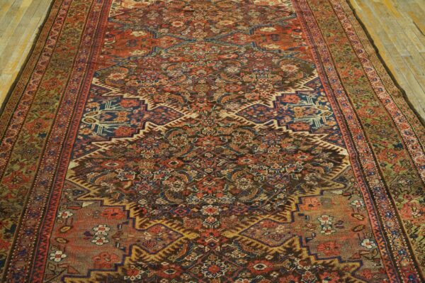 Muted red and blue traditional rug with complex pattern and central medallion on light wood flooring.