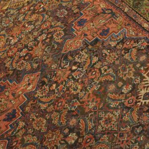 A low-pile rug with complex stepped geometric patterns in rust, dark blue, and dark brown.