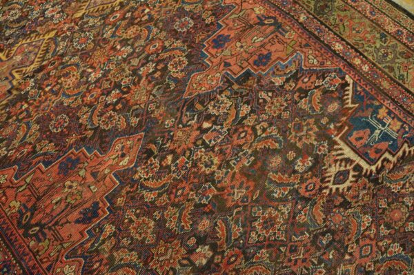 A low-pile rug with complex stepped geometric patterns in rust, dark blue, and dark brown.