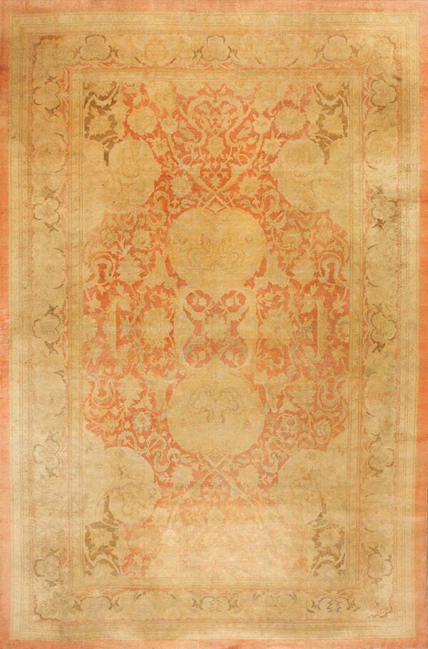 Traditional rug with a beige field and large ornate central medallion in coral and taupe.