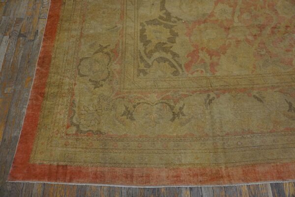 Low-pile, distressed gold and rust patterned rug detail displayed on dark, worn wood flooring.