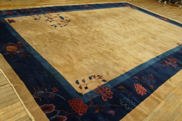 Golden field rug with a wide navy blue border and colorful floral designs on wood flooring.