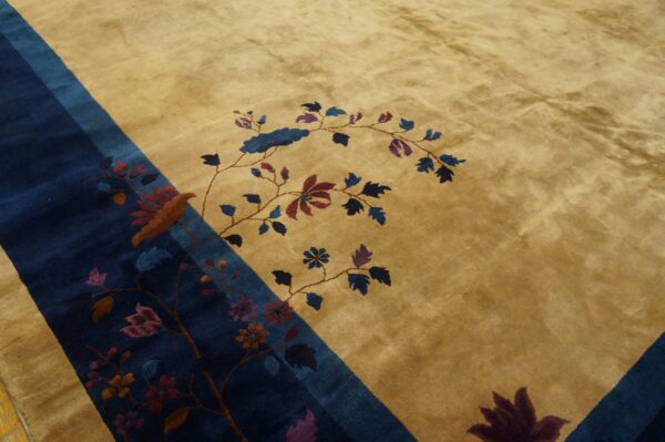 A gold rug features a stylized bird and vine pattern centered on a dark blue diagonal border.