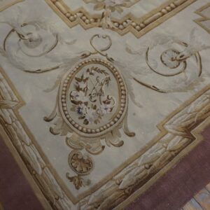 Ornate low-pile rug in cream and brown tones featuring a floral medallion detail on distressed wood planks.