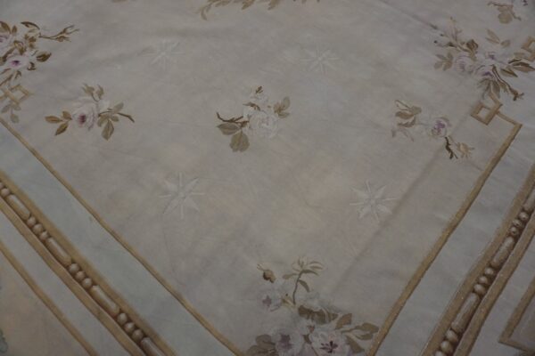 Smooth cream rug detail with diagonal texture, pale roses, recessed starbursts, and a detailed tan border.