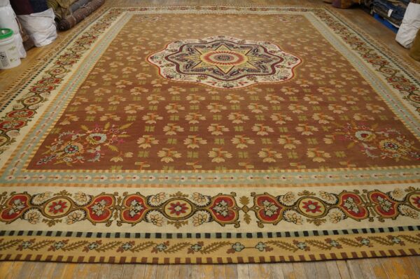 Large sienna-toned rug featuring a star medallion and intricate borders in red, cream, gold, and teal on wood flooring.