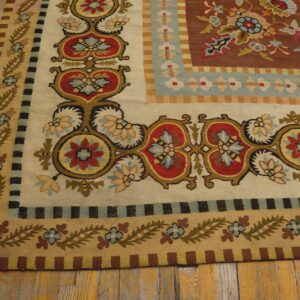 Ornate flatweave rug border featuring red, gold, and blue floral medallions resting on distressed wood flooring.