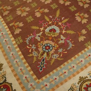 Flatweave rug detail showing a brown field, detailed floral motifs, and banded borders in light blue and cream.