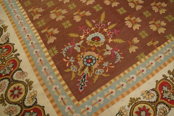 Flatweave rug detail showing a brown field, detailed floral motifs, and banded borders in light blue and cream.