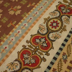 Flatweave rug with brown floral motifs, striped borders, and intricate red and cream medallion designs.