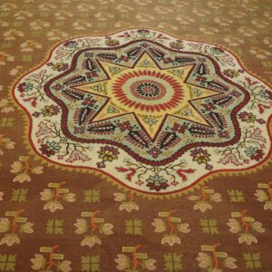 Brown rug featuring a vibrant, multicolored eight-pointed star medallion and stylized floral field patterns.
