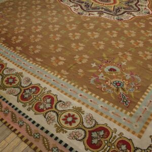 Ornate multi-border tan and brown rug with floral medallions resting on exposed wood floor planks.