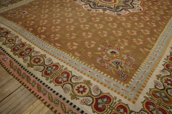 Ornate multi-border tan and brown rug with floral medallions resting on exposed wood floor planks.