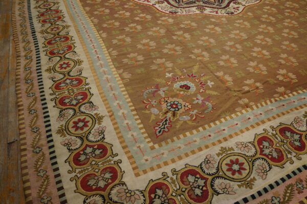 Detailed view of a low-pile rug with a brown field, small florals, and wide multi-banded red and cream borders.