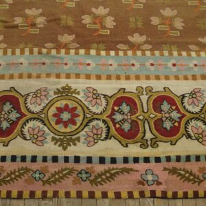 Multi-colored striped flatweave rug featuring large red and yellow medallions, small flowers, and brown and pink fields.