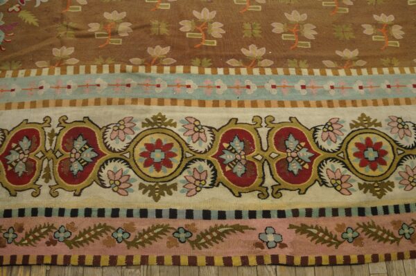 Multi-colored striped flatweave rug featuring large red and yellow medallions, small flowers, and brown and pink fields.