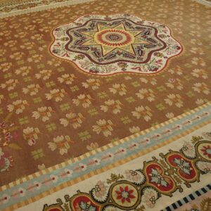 Multicolored flatweave rug featuring a central starburst on a reddish-brown field with ornate floral borders.