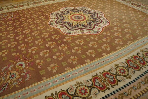 Multicolored flatweave rug featuring a central starburst on a reddish-brown field with ornate floral borders.