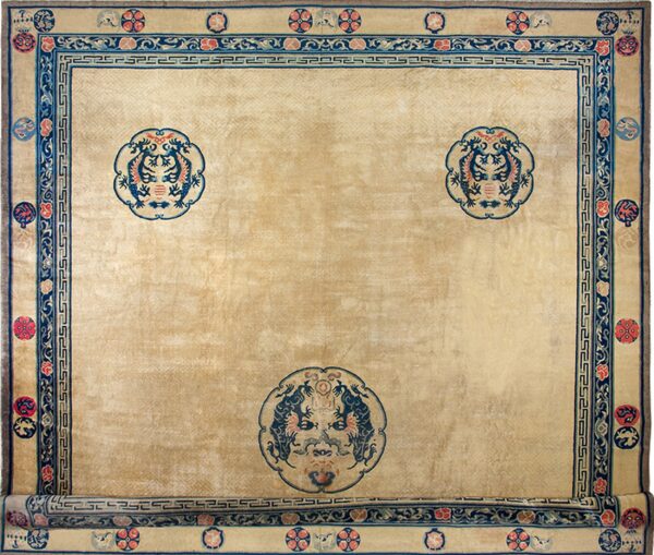 Tan field rug with complex blue and red borders and three large central stylized medallions.