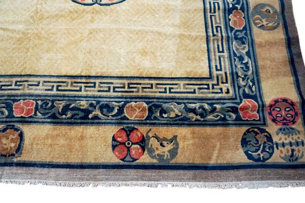Close-up of a cream and gold high-pile rug featuring blue greek key borders and floral medallions.