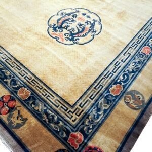 The corner of a pale gold rug showing blue borders, red flowers, and a central blue dragon motif.
